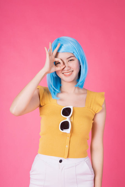 Portrait of a pretty excited asian girl with colorful shopping bags showing  isolated over pink background .Asian shopaholic woman carrying shopping bags in colorful for summer sale concept .young blue hair girl . - Foto, Imagen