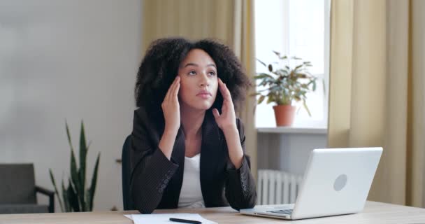 Cansada, agotada Afro chica aburrida de estudio de rutina de trabajo en la oficina en casa con el ordenador portátil, pierde energía, pone la cabeza sobre sus manos en la mesa, se duerme largo día en el lugar de trabajo, se siente perezosamente poco saludable - Metraje, vídeo