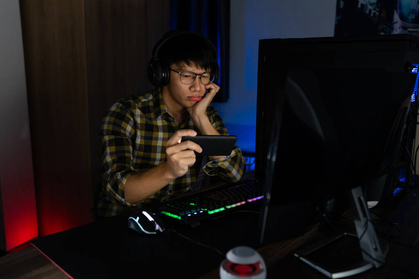 Hombre asiático jugador en auriculares estresado con la mano se siente deprimido o enojado conmocionado al perder el videojuego en el ordenador Miedo y molesto por error, la tecnología de videojuegos y el concepto de e-sport. - Foto, Imagen