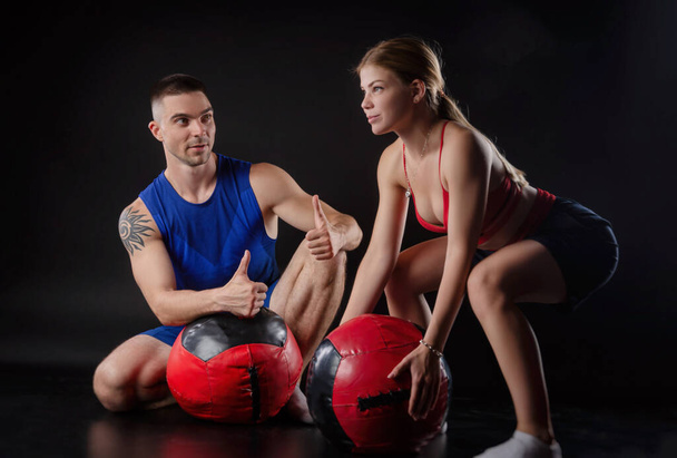a guy and a girl train with a heavy stuffed ball - Foto, imagen