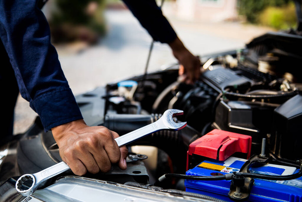 Close-up hand van auto monteur met behulp van moersleutel om een auto motor te repareren. concepten van auto onderhoud fix reparatie service en verzekering. - Foto, afbeelding
