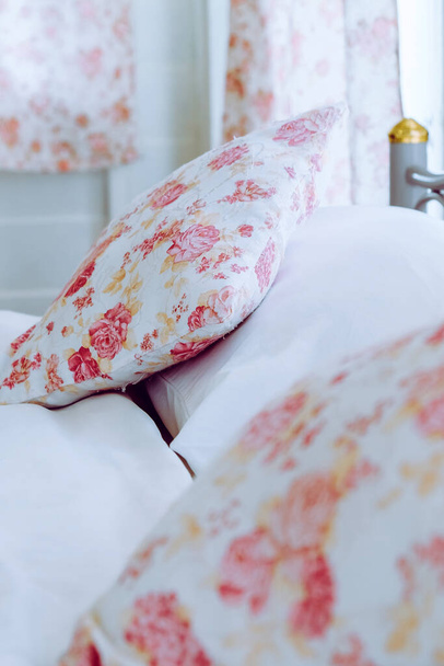 Φωτεινό εσωτερικό υπνοδωμάτιο με λουλούδι μοτίβο μαξιλάρια στο κρεβάτι  - Φωτογραφία, εικόνα