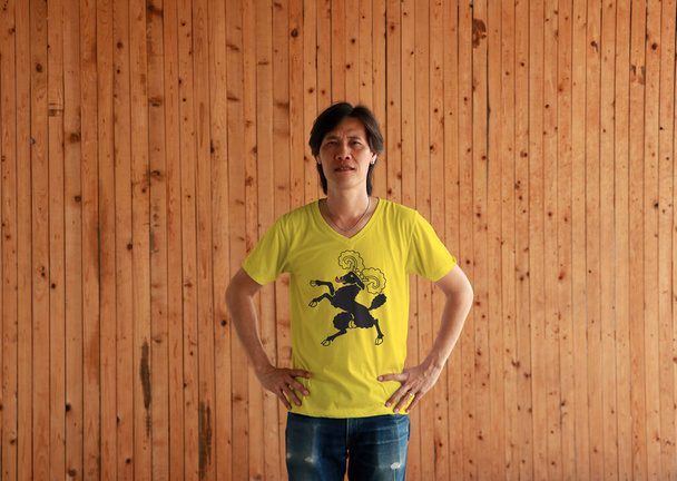 シャフハウゼン旗色のシャツを着て、木製の壁の背景にakimboと立っている男。スイス連邦の州. - 写真・画像