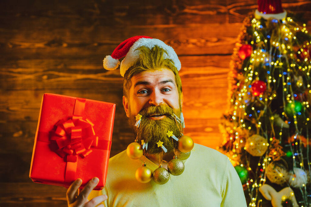 Delivery gifts. New Year, Christmas card. Hipster modern Santa Claus wishes Merry Christmas. Styling Santa Claus with a long beard posing on the wooden background. - Photo, image