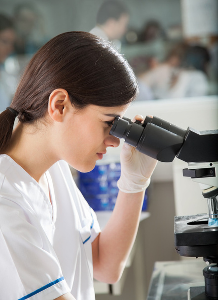 Female Researcher Looking Into Microscope In Lab - Foto, immagini