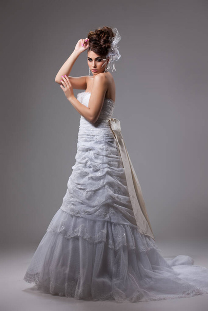 Young beautiful woman in a wedding dress on a studio background - Fotó, kép