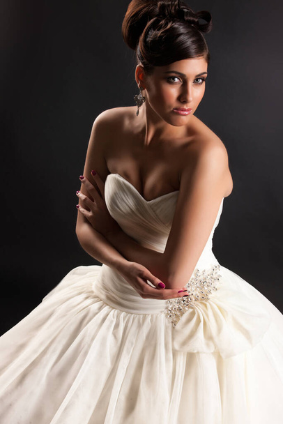 Young beautiful woman in a wedding dress on a black studio background - Foto, imagen