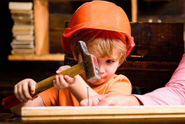 Funny little repairman with hammer. Kids construction worker. Child use a hammer to nail. - Photo, Image