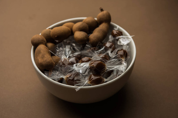 Tamarind Bonbons oder Imli Pops werden aus Tamarindus Indica Fruchtfleisch und Zucker oder Zackenbarsch hergestellt und in kleine Plastikverpackungen gewickelt, die an jedem Ende verdreht sind. - Foto, Bild