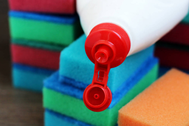 Esponjas de cocina de colores y botella de líquido lavavajillas, fondo de madera - Foto, Imagen