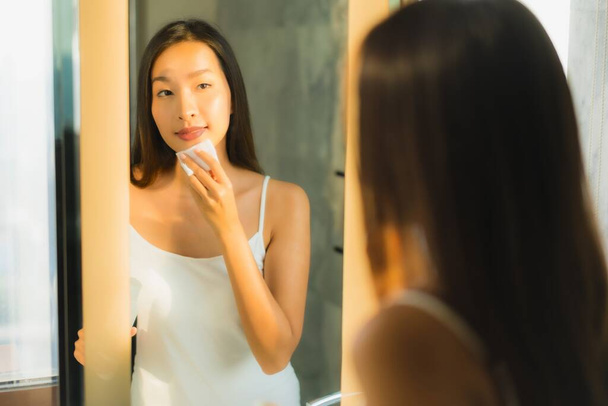 Portrait beautiful young asian woman clean her face and facial with mirror in bathroom interior - Fotó, kép