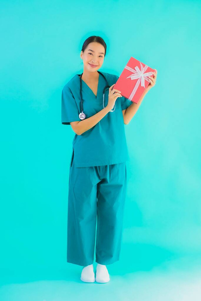 Retrato hermosa joven asiática médico mujer show rojo regalo caja en azul aislado fondo
 - Foto, imagen