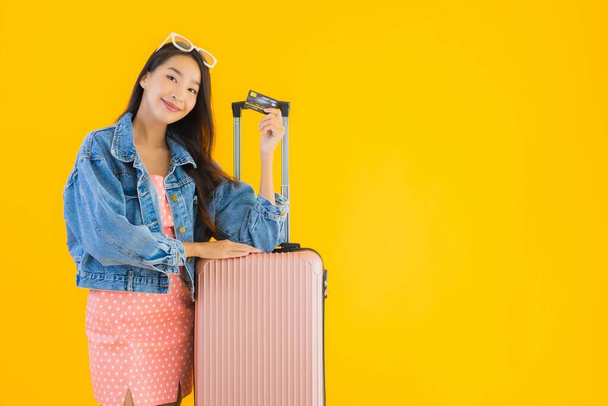 Ritratto bella giovane donna asiatica con bagaglio borsa da viaggio con passaporto e biglietto d'imbarco su sfondo giallo isolato
 - Foto, immagini