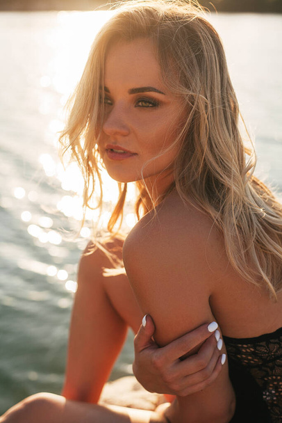 Sexy blonde Frau im schwarzen Badeanzug posiert am Strand - Foto, Bild