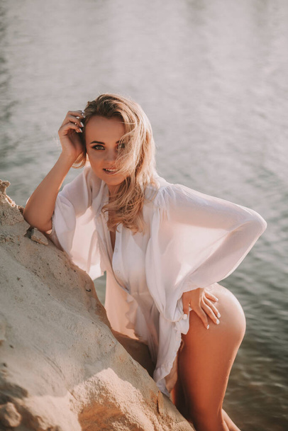 Сексуальная блондинка в черном купальнике позирует на пляже - Фото, изображение
