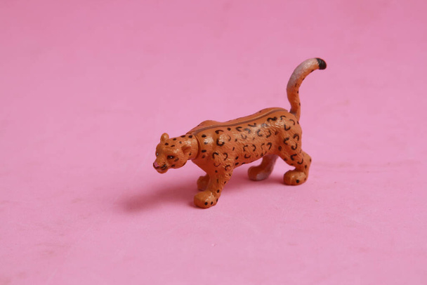 A small leopard plastic toy on a pink background - Foto, Imagem