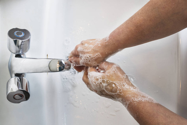 Una toma aérea de un hombre lavándose las manos con jabón espumoso en un hundimiento COVID-19, concepto de coronavirus - Foto, imagen