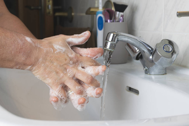 Um tiro de perto de um macho a lavar as mãos com sabão espumoso COVID-19, conceito de coronavírus
 - Foto, Imagem