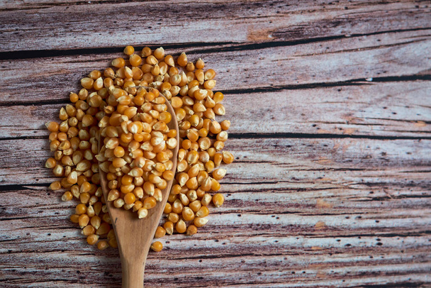 A top view closeup shot of a wooden spoon full corn kernels with some of it piled on the side - Photo, Image