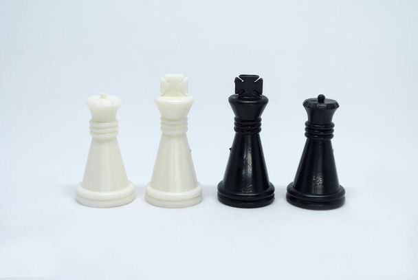 Выбранные черно-белые шахматные фигуры все вместе расположены случайным образом на белом фоне.  - Фото, изображение