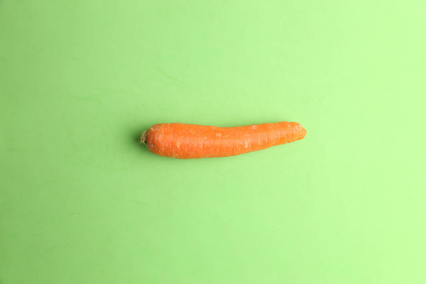 A fresh organic carrot on a green surface - Foto, afbeelding
