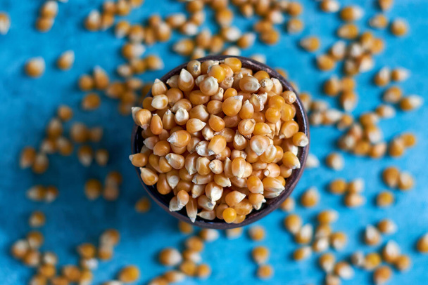 A top view closeup shot of a container full corn kernels with some of it scattered on the side - Fotó, kép