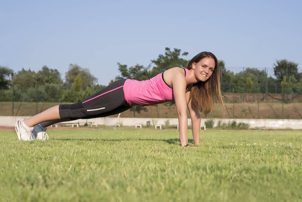 A shallow focus shot of a sporty Caucasian female doing a workout in the park - Fotó, kép