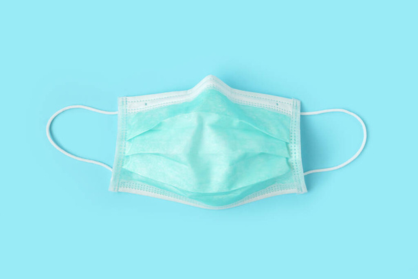 Surgical face mask on blue background protection against COVID-19 coronavirus. Healthcare and medical concept - Photo, Image