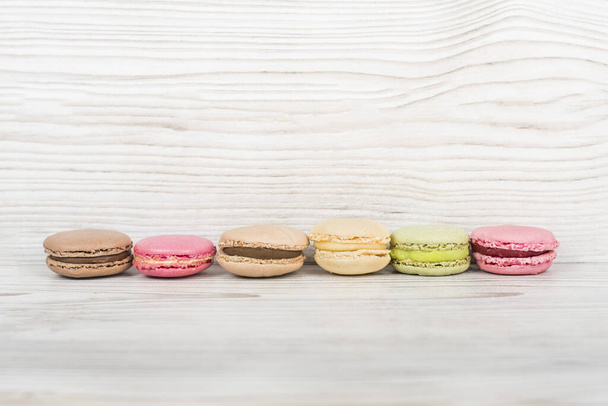 A selective focus shot of colorful macaroons on wooden table - Fotoğraf, Görsel