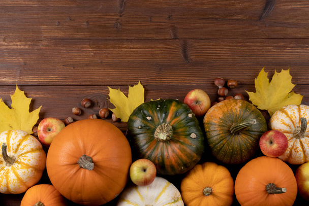 Autumn harvest still life with pumpkins , apples , hazelnuts on wooden background , top view - Foto, imagen
