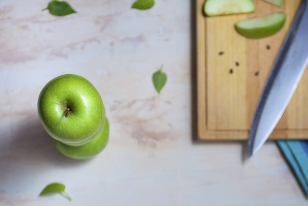 A top view of shining green apple next to blurred wooden cutting board - Foto, afbeelding