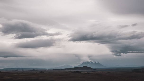 A horizontal shot of a landscape in Iceland showing a volcano in the distance and cloudy sky - Foto, Bild