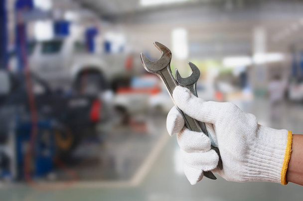 Technicien tenant une clé avec arrière-plan du centre de service de réparation automobile - Photo, image
