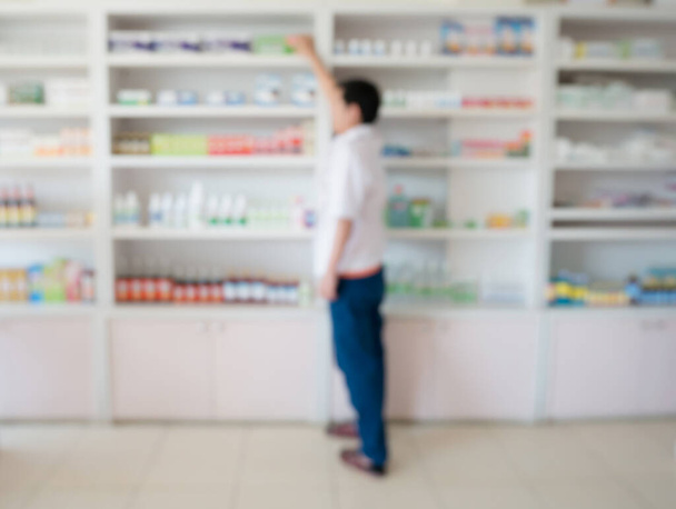 blur image of pharmacist taking medicine from shelf in the pharmacy - Photo, Image