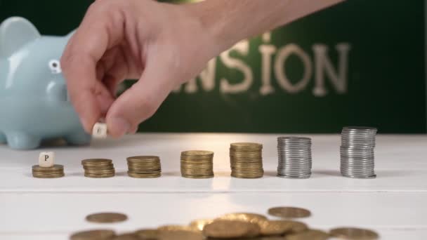 Composición con monedas apiladas y palabra PENSIÓN en la mesa - Imágenes, Vídeo
