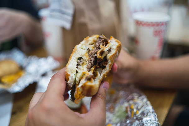 A closeup shot of a burger filled with sauce and meat - Foto, Imagem