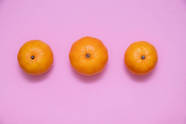 Three fresh mandarins on a pink surface - Photo, Image