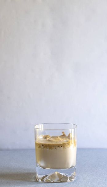 A vertical selective focus shot of a glass of coffee on a blue surface - Фото, изображение