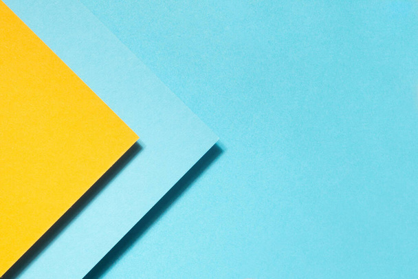 A high angle shot of yellow and blue papers in geometric shapes on a blue background - Φωτογραφία, εικόνα