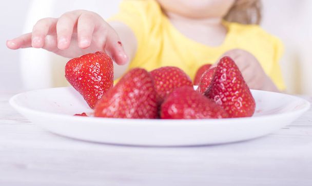 A closeup shot of a little girl eating strawberries - Photo, image