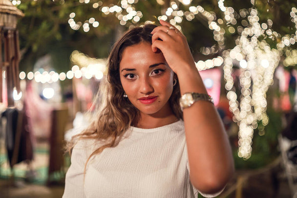 A beautiful shot of a young caucasian female with Christmas lights background - Fotó, kép