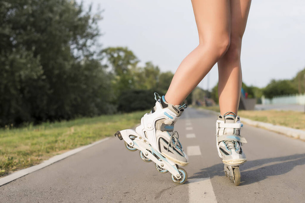 A woman wearing the roller skates and standing on the ground - Foto, Bild