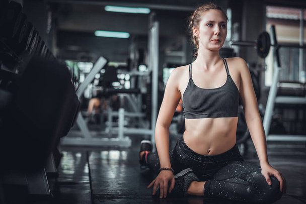 Der filmische Ton der jungen attraktiven Fitness-Frau, die mit einem Gerät im Fitnessstudio trainiert. Individueller Sport, um die Muskeln des Körpers für ein gesundes Lebenskonzept fit zu machen.  - Foto, Bild