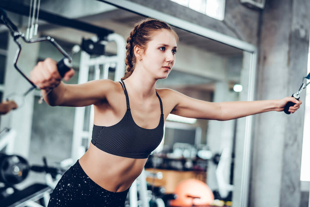 Cinematic ton młody atrakcyjny fitness kobieta ćwiczenia z maszyny w siłowni. Indywidualny sport dopasować mięśnie ciała dla zdrowej koncepcji życia.  - Zdjęcie, obraz