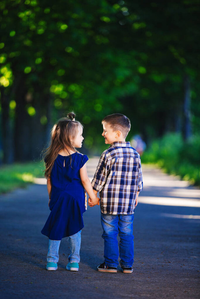 L'amour des enfants, un petit garçon et une fille, s'amuser, rire et sourire, et s'embrasser à l'extérieur. vue arrière - Photo, image