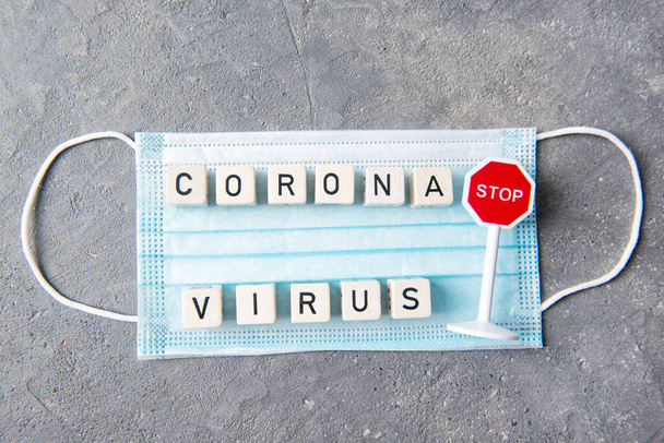 Masque jetable bleu avec lettres et texte corona virus et stop sign, vue du dessus, concept de santé - Photo, image