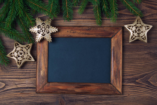 Merry Christmas decorations, empty chalkboard and frame made of fir, snowflake and stars on a timber background - Zdjęcie, obraz