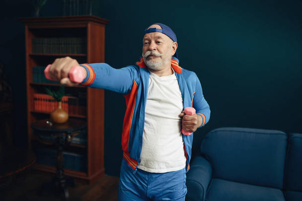 Idős sportoló egyenruhában, otthon edz. Felnőtt férfi személy fitness képzés beltéri, egészséges életmód idős korban - Fotó, kép