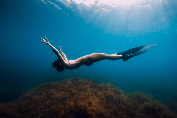 Női szabadúszó, uszonyokkal, akik a kék tengeren pihennek. Nő víz alatt és reflexió - Fotó, kép