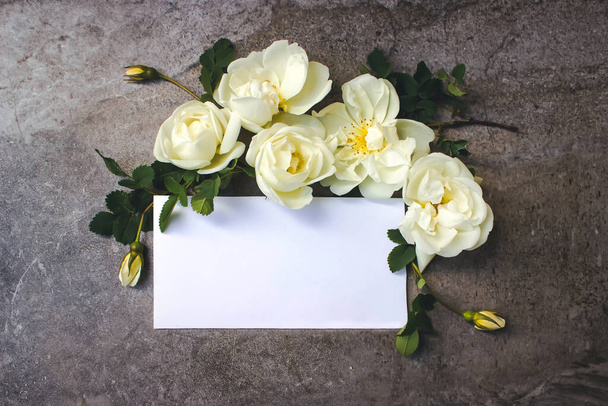 Στεφάνι γάμου με λευκά τριαντάφυλλα και καθαρό χαρτί κενό. Επίπεδο lay, πάνω όψη - Φωτογραφία, εικόνα